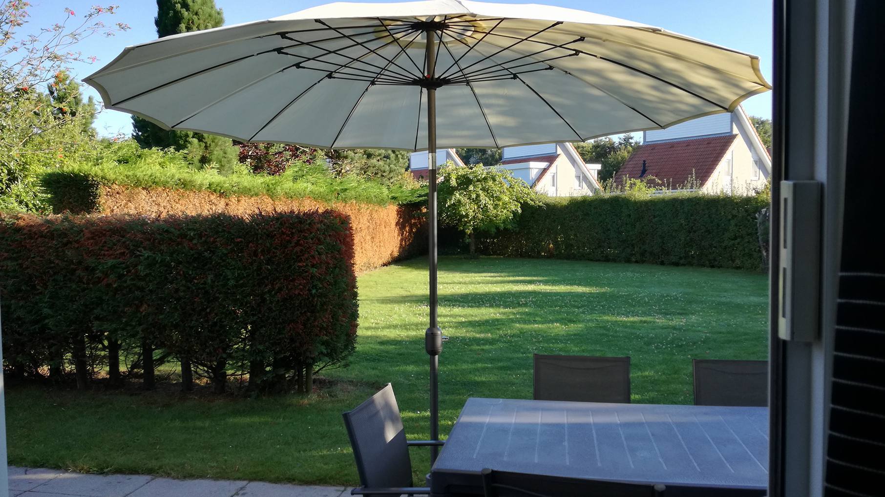 Blick über die Terasse des Ferienhauses in den großen Garten